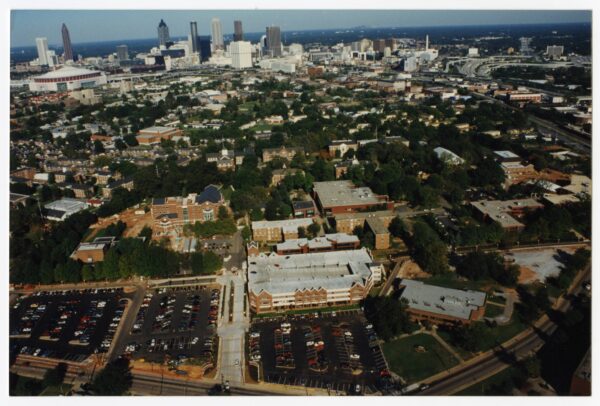 An aerial view of Spelman College campus buildings and the tree canopy with large downtown skyscrapers in the background.