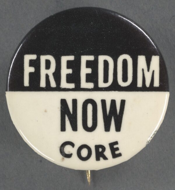 A black and white pin-back button with text. The top half of the button has a black background with 