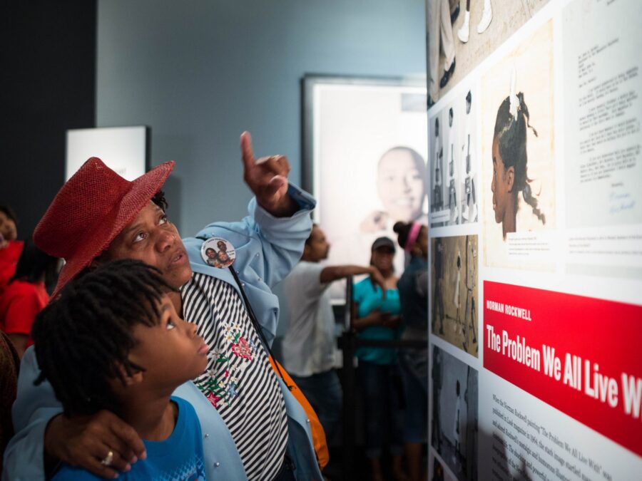 Center volunteer highlights primary resources within exhibition panels.