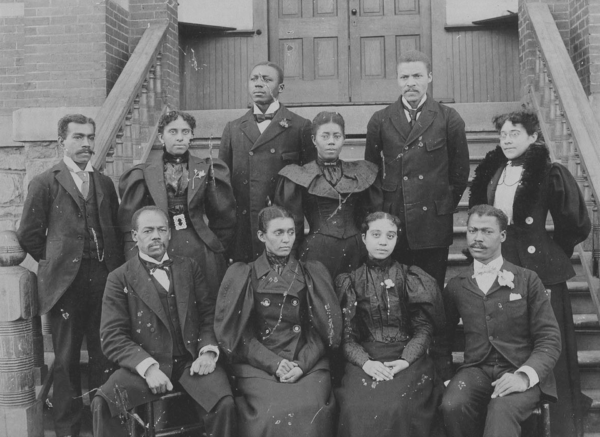 Group portrait of African American faculty and staff seated and standing on steps outside a building at Morris Brown College, dressed in formal late 19th-century clothing