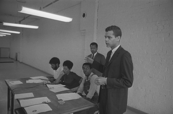 Julian Bond speaks at a SNCC press conference in Atlanta in 1966, standing beside seated members including Stokely Carmichael, Ruby Robinson, and Cleveland Sellars