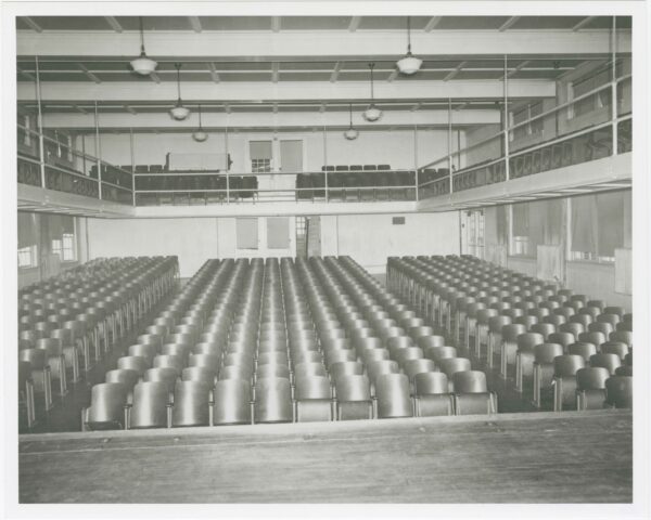 Large and clean auditorium with many rows of built-in seating and a balcony with additional seating.